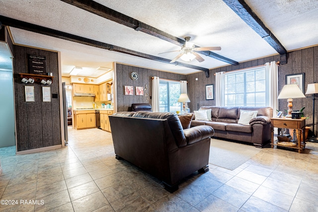 living room with beam ceiling, ceiling fan, and a textured ceiling