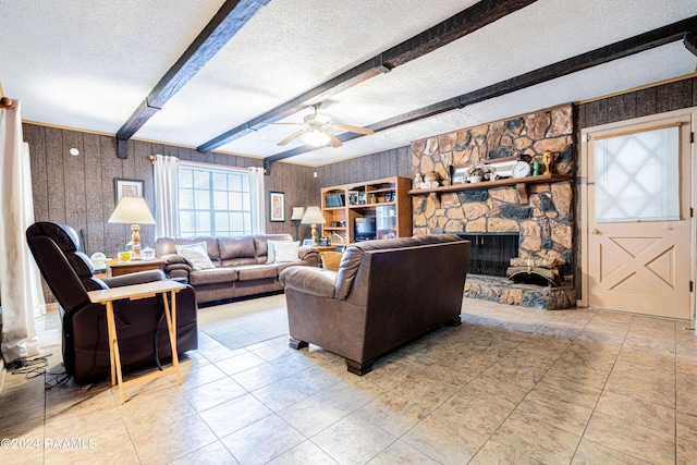 living room with beamed ceiling, a fireplace, and a textured ceiling