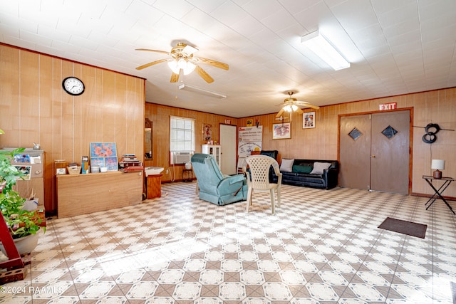 living room with ceiling fan, wooden walls, and light tile floors