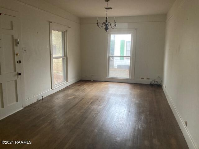 spare room featuring a chandelier and dark hardwood / wood-style flooring