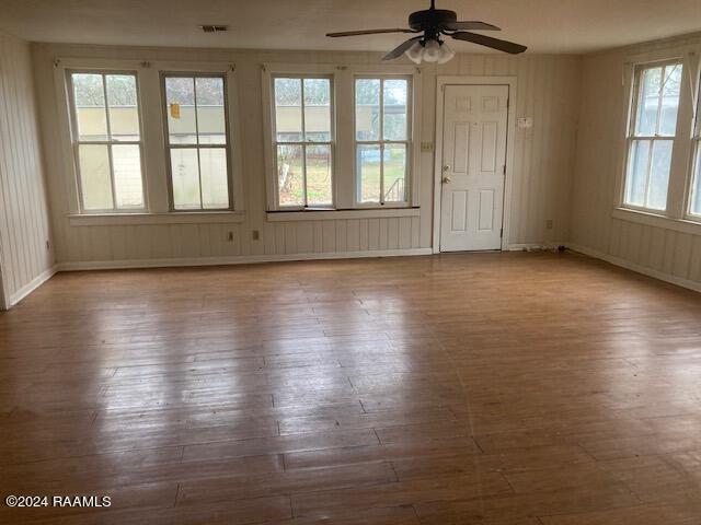 unfurnished room with hardwood / wood-style floors, ceiling fan, and a wealth of natural light