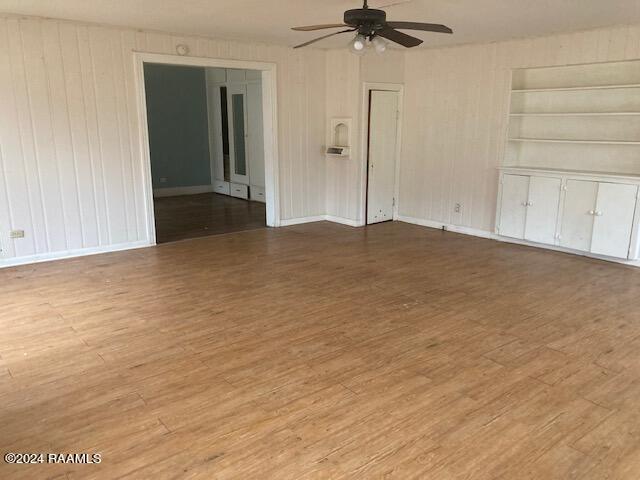 unfurnished room with built in features, ceiling fan, and light hardwood / wood-style flooring