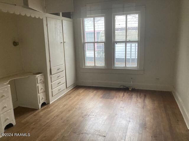 unfurnished bedroom with hardwood / wood-style floors and multiple windows