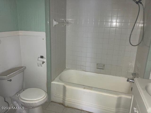 full bathroom with tiled shower / bath combo, tile floors, toilet, and vanity