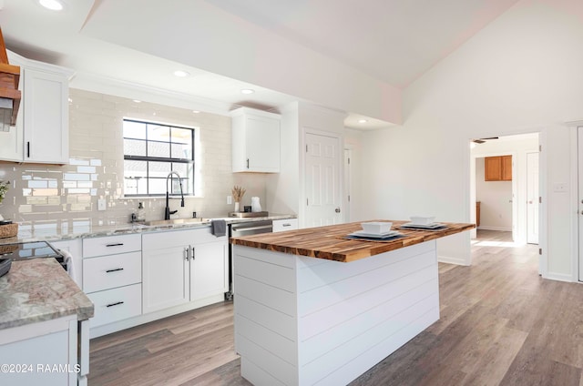 kitchen featuring sink, backsplash, a center island, white cabinetry, and light wood-type flooring