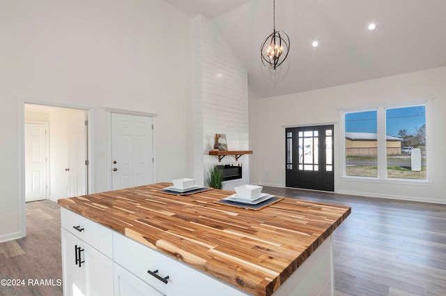 kitchen with pendant lighting, light hardwood / wood-style floors, wooden counters, white cabinets, and an inviting chandelier