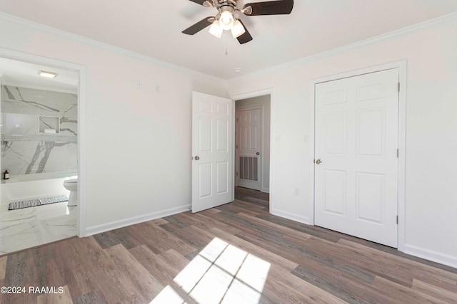 unfurnished bedroom with ceiling fan, dark wood-type flooring, ornamental molding, and ensuite bathroom