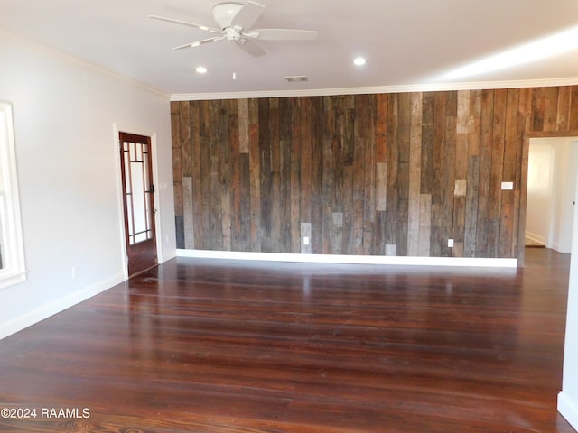 unfurnished room featuring wooden walls, ceiling fan, dark wood-type flooring, and ornamental molding