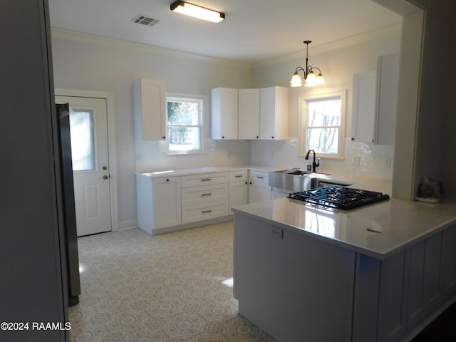 kitchen with an inviting chandelier, white cabinets, tasteful backsplash, and a healthy amount of sunlight