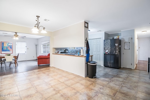 kitchen with decorative light fixtures, black refrigerator, light tile floors, kitchen peninsula, and ceiling fan with notable chandelier