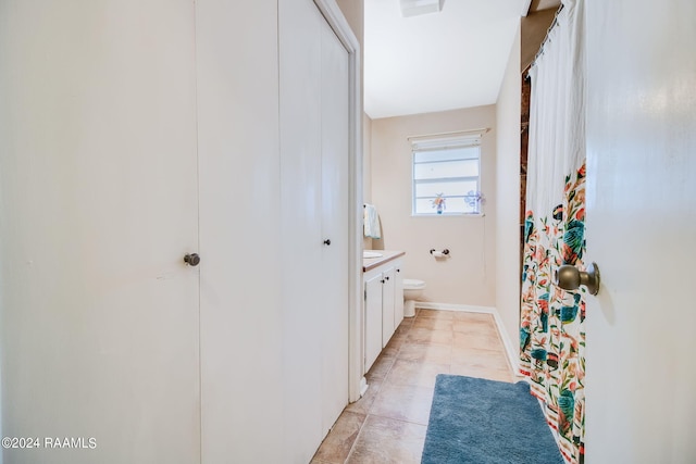 bathroom with toilet, vanity, and tile flooring