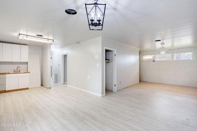 unfurnished living room with brick wall, sink, ornamental molding, ceiling fan, and light hardwood / wood-style flooring