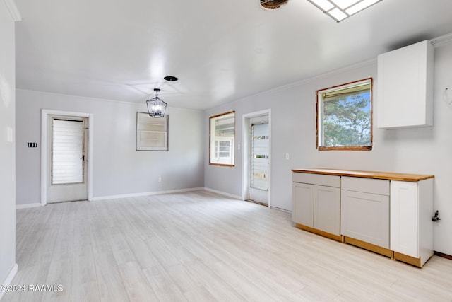 unfurnished living room with light hardwood / wood-style flooring, ornamental molding, and plenty of natural light