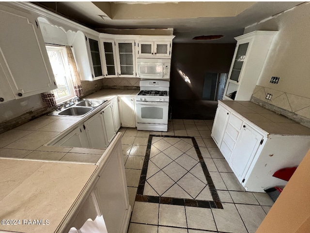 kitchen with white appliances, sink, light tile flooring, tasteful backsplash, and white cabinetry