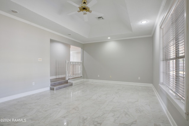 tiled empty room featuring a raised ceiling, ceiling fan, and ornamental molding