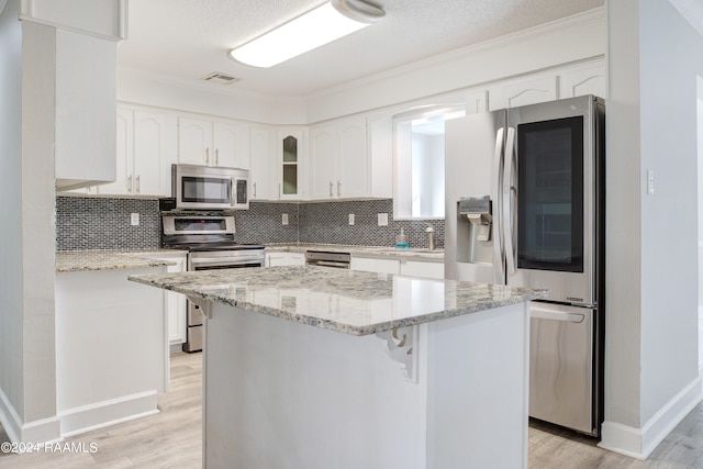 kitchen with appliances with stainless steel finishes, a breakfast bar, white cabinetry, and light hardwood / wood-style floors