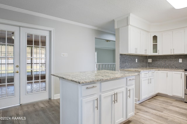 kitchen with white cabinets, tasteful backsplash, light hardwood / wood-style flooring, and light stone counters