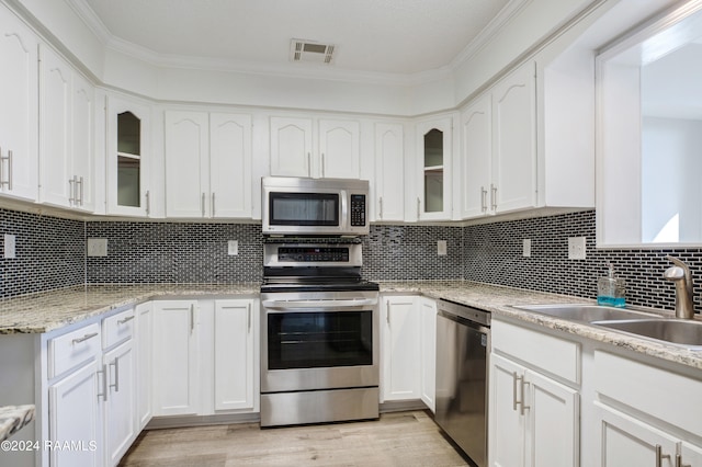 kitchen featuring white cabinets, tasteful backsplash, light wood-type flooring, and stainless steel appliances