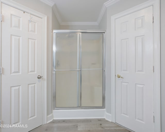 bathroom with a shower with shower door, ornamental molding, and hardwood / wood-style flooring