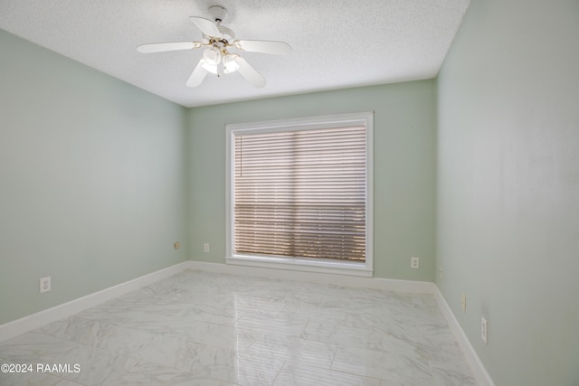 unfurnished room featuring plenty of natural light, a textured ceiling, ceiling fan, and light tile flooring