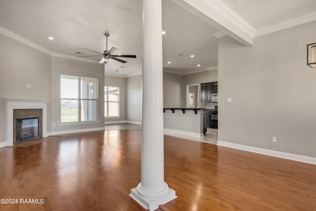 unfurnished living room with hardwood / wood-style floors, ornate columns, crown molding, and ceiling fan with notable chandelier