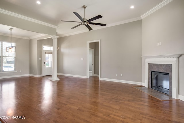 unfurnished living room featuring dark hardwood / wood-style flooring, ceiling fan with notable chandelier, ornate columns, and a wealth of natural light