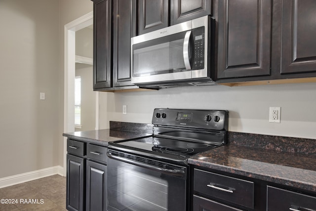 kitchen with black range with electric stovetop, ornamental molding, dark tile flooring, dark brown cabinetry, and dark stone countertops