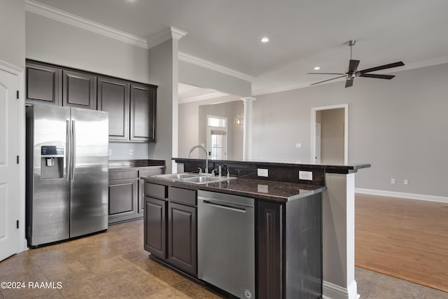 kitchen featuring an island with sink, ceiling fan, sink, appliances with stainless steel finishes, and decorative columns