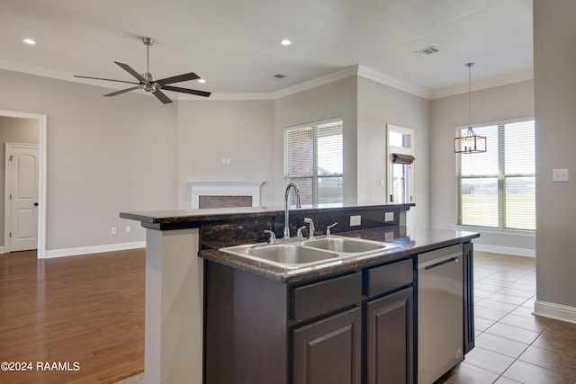 kitchen with an island with sink, ceiling fan with notable chandelier, a healthy amount of sunlight, and light hardwood / wood-style flooring