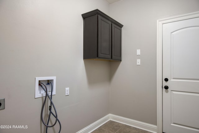 laundry room featuring dark tile flooring, hookup for a washing machine, and cabinets