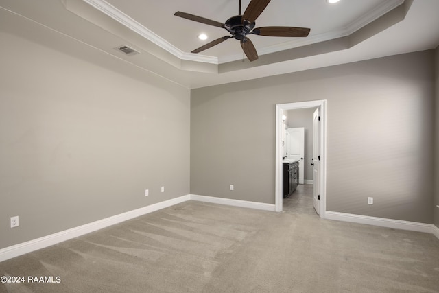 unfurnished bedroom with ceiling fan, connected bathroom, a tray ceiling, and light colored carpet