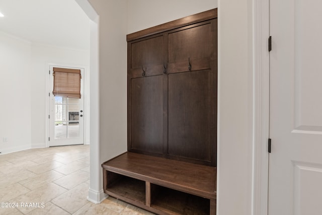 mudroom with crown molding and light tile patterned floors