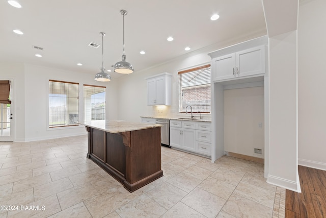 kitchen with white cabinets, sink, hanging light fixtures, a kitchen island, and a kitchen bar