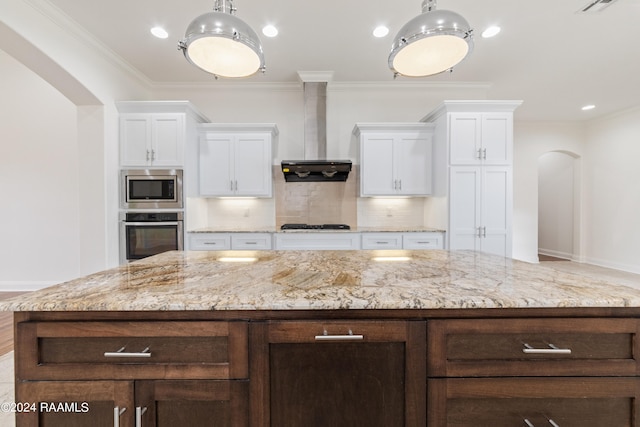 kitchen featuring white cabinets, appliances with stainless steel finishes, crown molding, and wall chimney exhaust hood