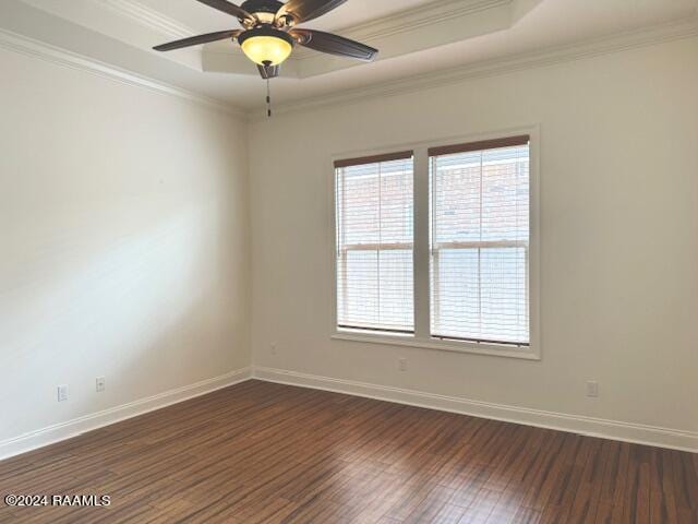 unfurnished room with a raised ceiling, dark hardwood / wood-style floors, and ornamental molding