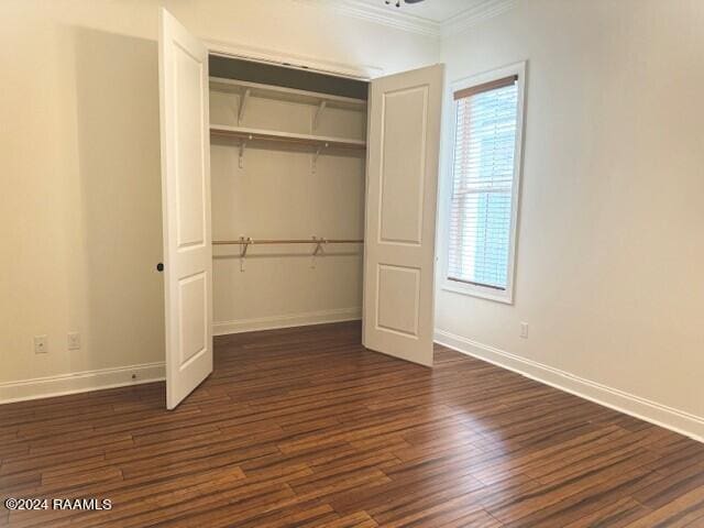 unfurnished bedroom with crown molding, a closet, and dark hardwood / wood-style floors