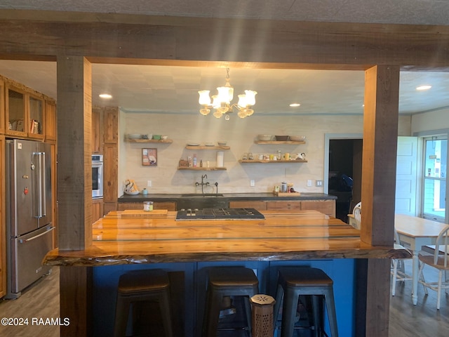 kitchen with butcher block countertops, a breakfast bar, appliances with stainless steel finishes, and a chandelier