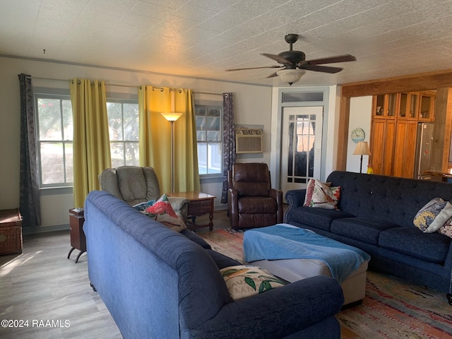 living room featuring light hardwood / wood-style floors, ceiling fan, and a wall mounted AC
