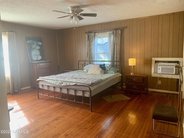 bedroom featuring wooden walls, dark hardwood / wood-style floors, and ceiling fan