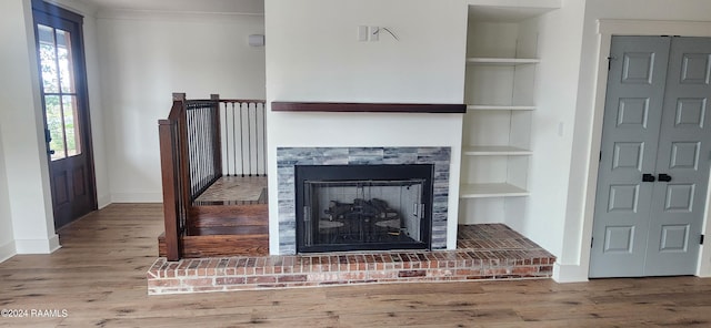 living room featuring built in features, hardwood / wood-style flooring, and a brick fireplace