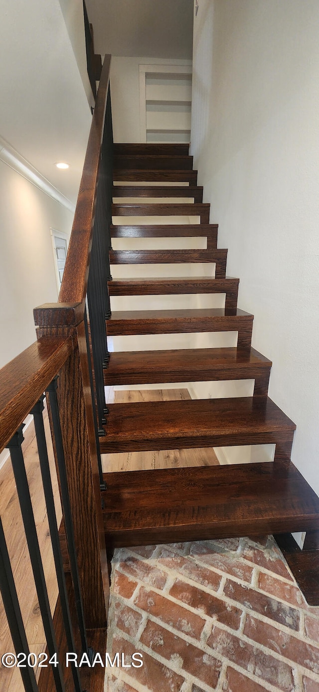 stairs featuring hardwood / wood-style floors and ornamental molding