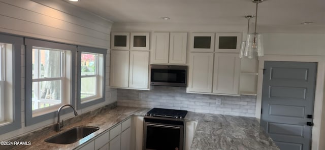 kitchen with hanging light fixtures, stainless steel appliances, sink, decorative backsplash, and white cabinets