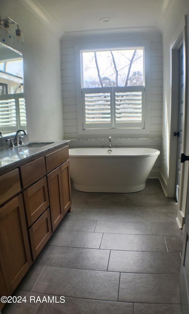 bathroom with a tub, ornamental molding, and vanity