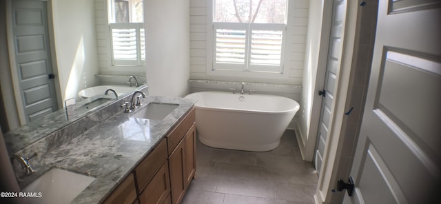 bathroom with tile patterned floors, a healthy amount of sunlight, a bathtub, and vanity