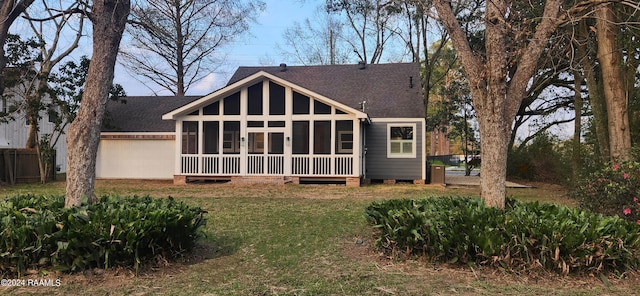 rear view of house with a yard and a sunroom