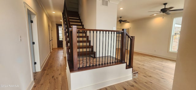 stairway featuring wood-type flooring, crown molding, and ceiling fan