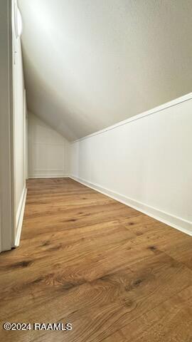 bonus room with hardwood / wood-style flooring and vaulted ceiling