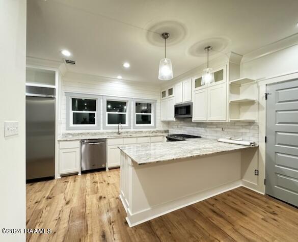 kitchen featuring light wood-type flooring, appliances with stainless steel finishes, white cabinetry, kitchen peninsula, and pendant lighting