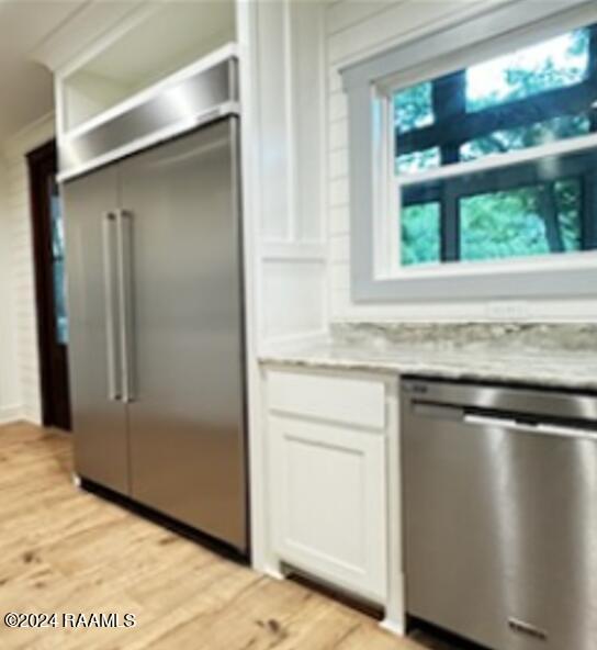 kitchen featuring light wood-type flooring, appliances with stainless steel finishes, and white cabinets