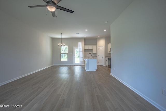 unfurnished living room featuring ceiling fan with notable chandelier, sink, and light hardwood / wood-style flooring